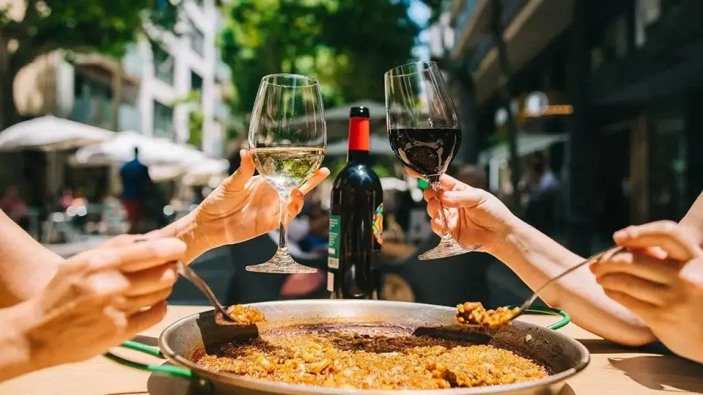 a couple enjoying their txueleton, best tapas and pintxos as lunch in a street restaurant with wine and champagne in barcelona