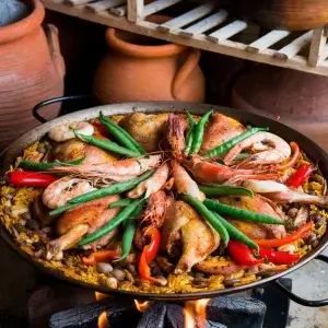 Traditional Spanish paella with rice, chicken, rabbit, and shrimp in a rustic setting - History of Paella